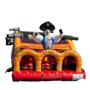 Inflatable pirate-themed obstacle course bounce house with cannons, pirate figure, and red entry arches for children's entertainment.